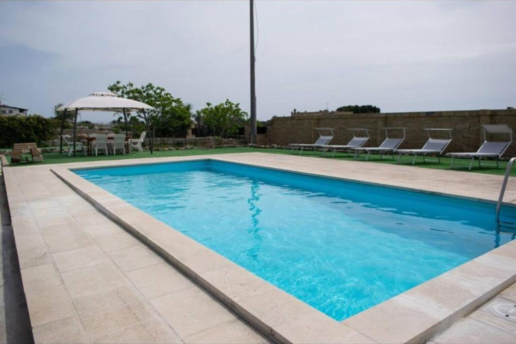 una piscina con agua azul, sillas y sombrilla en Villa Perilli - Luxury Stay con piscina privata, en Diso