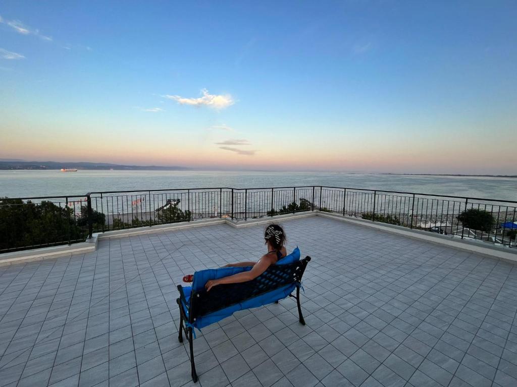 una mujer sentada en un banco mirando el océano en Finestra sul mare, en Monfalcone