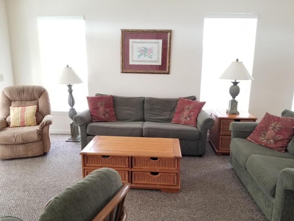 ein Wohnzimmer mit Sofas, Stühlen und einem Couchtisch in der Unterkunft Seaside at Anastasia 306 in Saint Augustine Beach