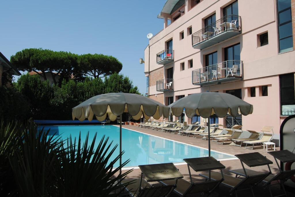 uma piscina do hotel com cadeiras e guarda-sóis em Hotel Capriccio em Cervia