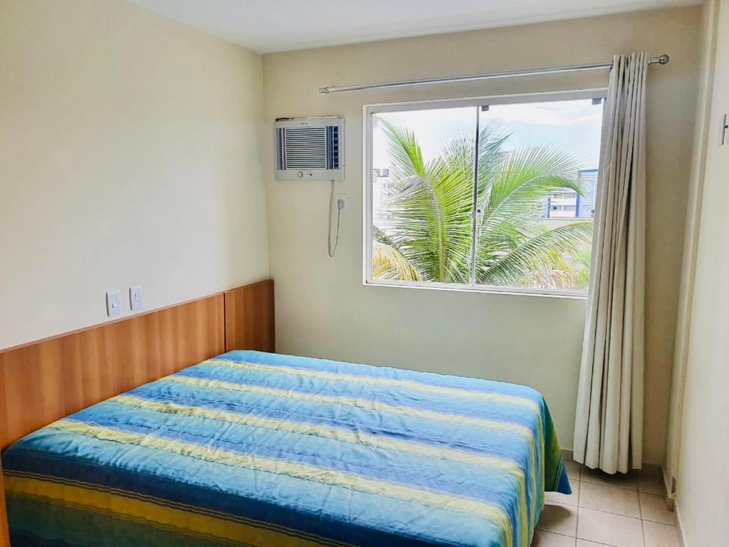 a bedroom with a bed and a window with a palm tree at Flat Pertinho do Hot Park (200m)! Aconchegante! in Rio Quente