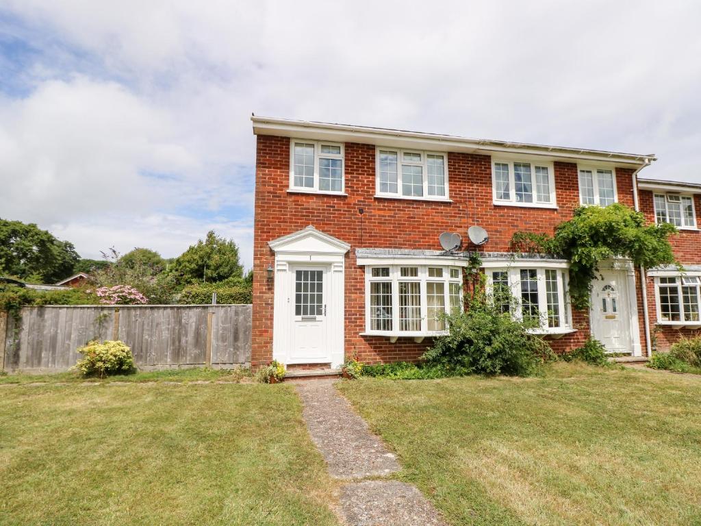 una casa de ladrillo con una puerta blanca y una valla en 1 Westwood Close, en Cowes