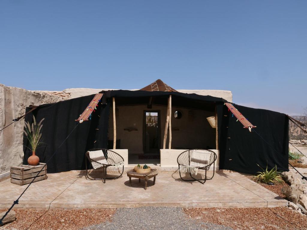 une tente noire avec des chaises et une table devant elle dans l'établissement Berber Beldi Camp, à Imsouane