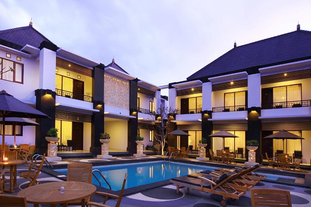 a hotel with a swimming pool and tables and chairs at The Radiant Hotel & Spa in Kuta