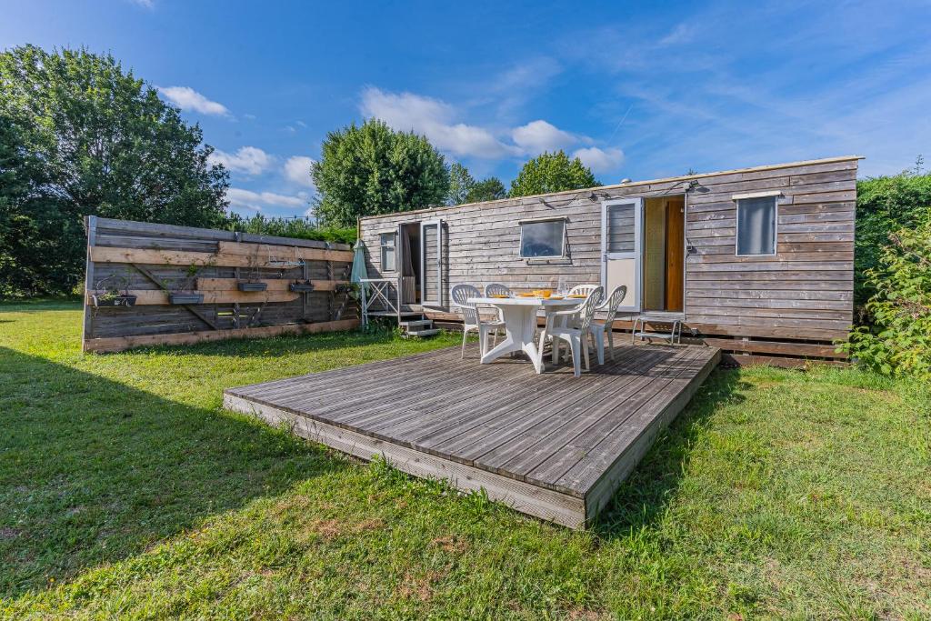- une terrasse en bois avec une table et des chaises devant une caravane dans l'établissement Mobilhome Vintage Biscarrosse, à Biscarrosse