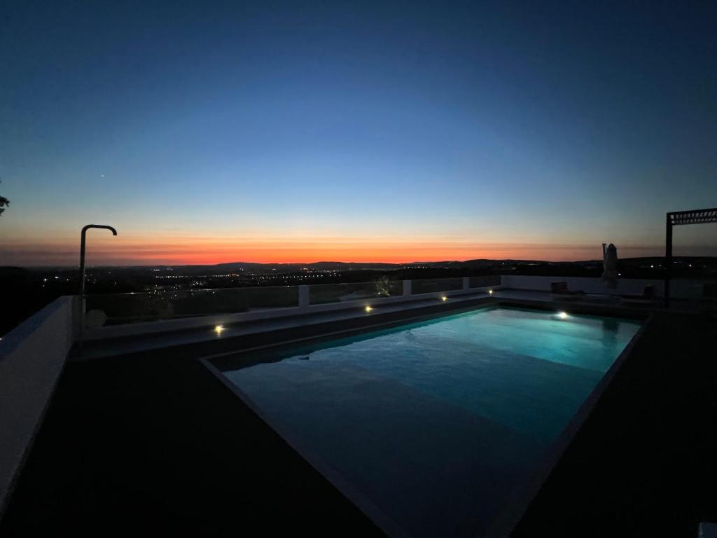 Goldra de Baixo的住宿－villagoldra rentals - Luxury and Family Villa，日落时分在大楼顶部的游泳池