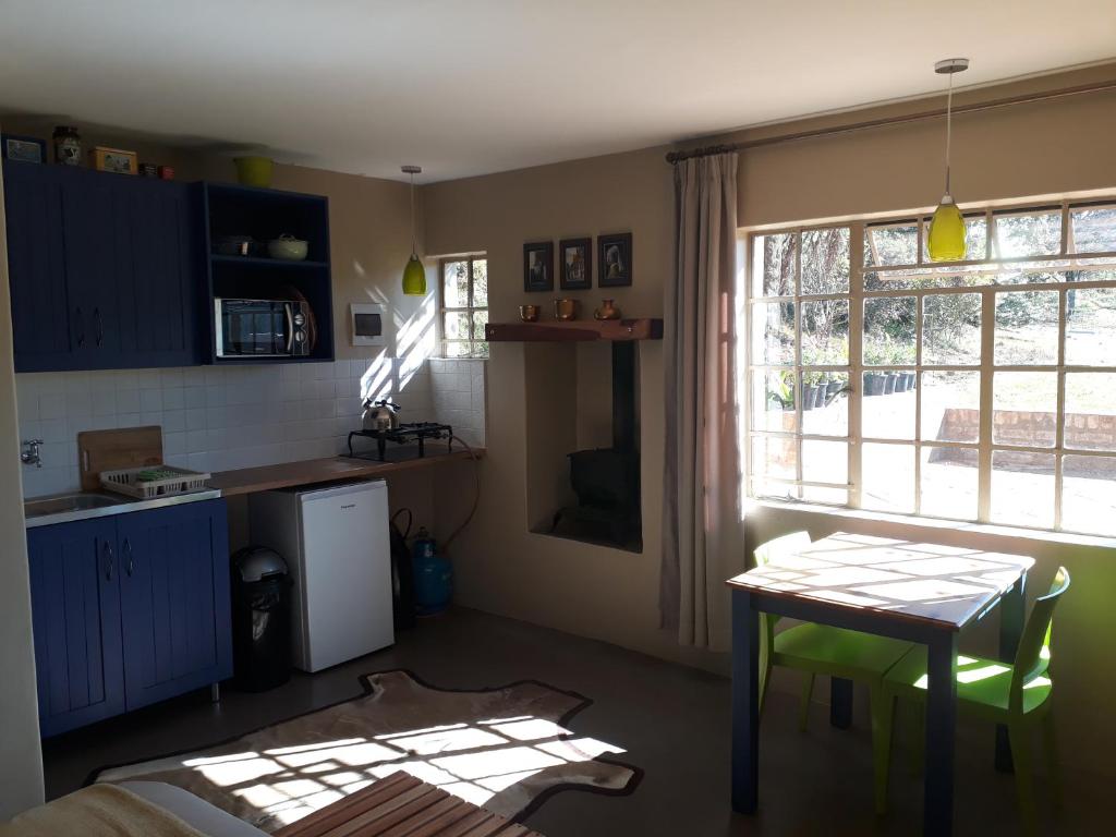 a room with a table and a kitchen with a window at Kaltenbach Cottages in Magoebaskloof