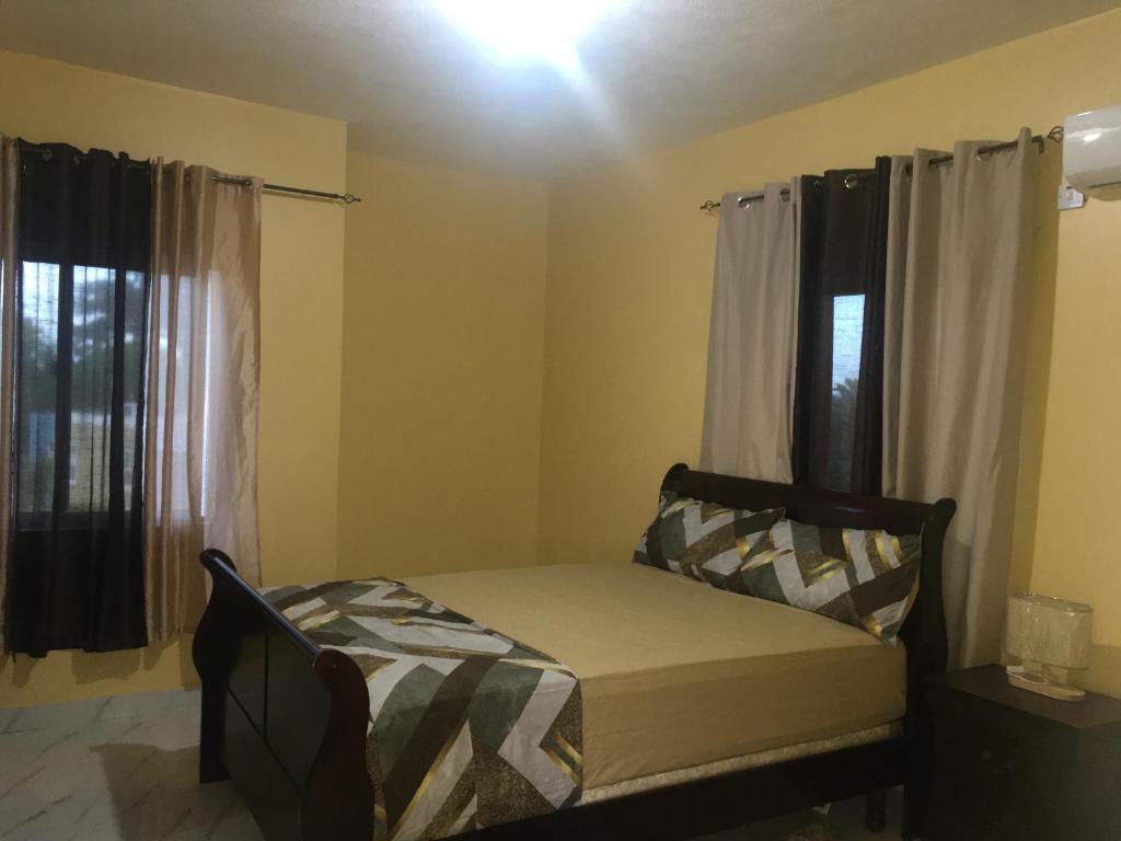 1 dormitorio pequeño con 1 cama y 2 ventanas en Treasures Gated Community Spot, en Spanish Town