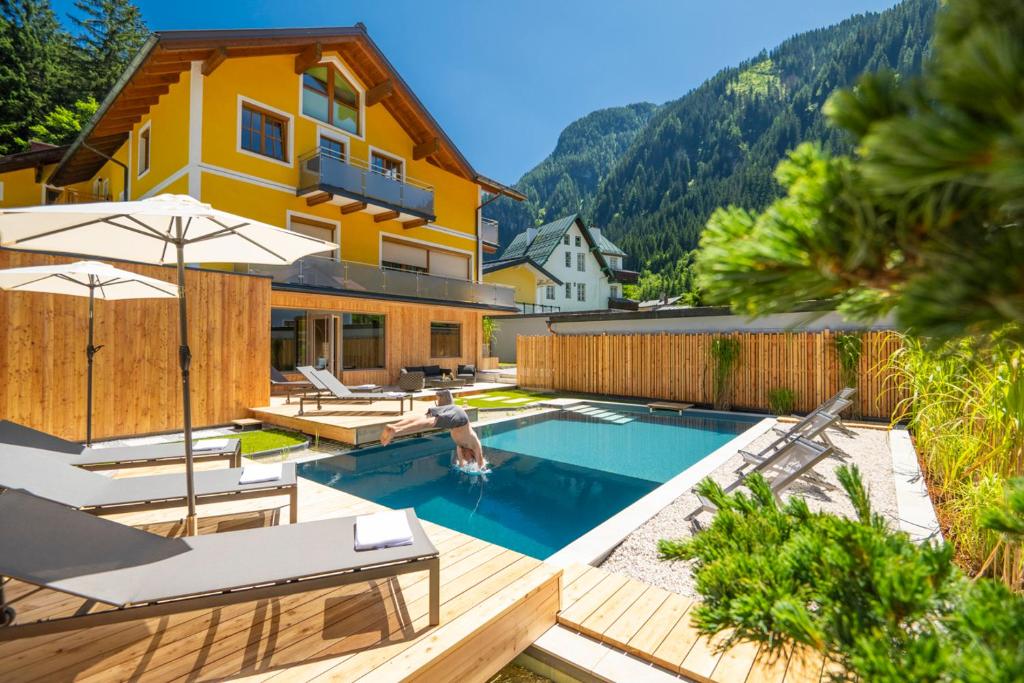 une maison avec une piscine et une maison dans l'établissement AlpinSpa zur Post, à Bad Gastein