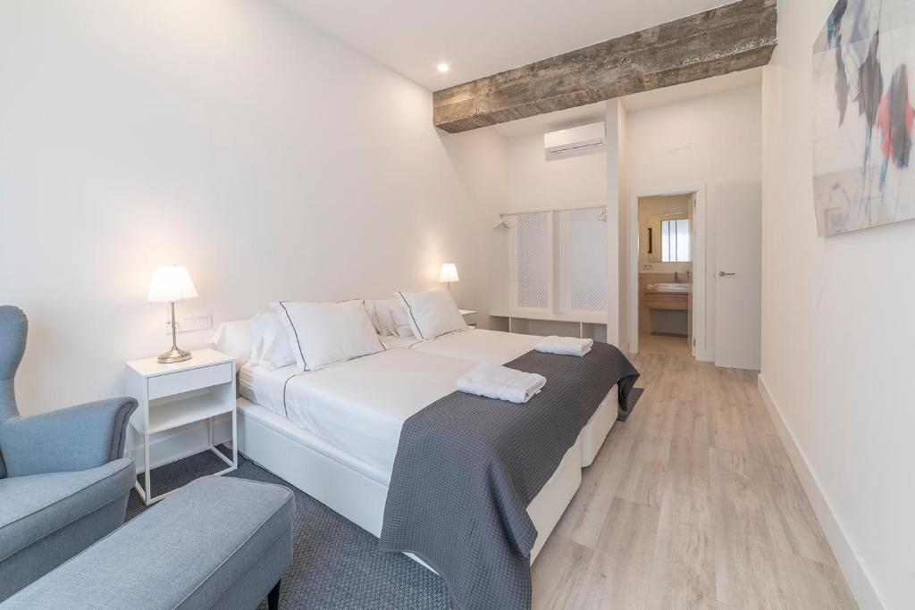 1 dormitorio con 1 cama blanca grande y 1 sofá en AlohaMundi Segovia&Fortaleza, en Sevilla