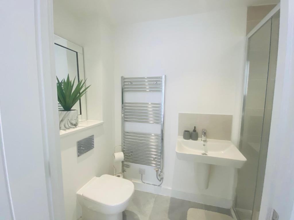 Baño blanco con aseo y lavamanos en Stylish New Built en Mánchester
