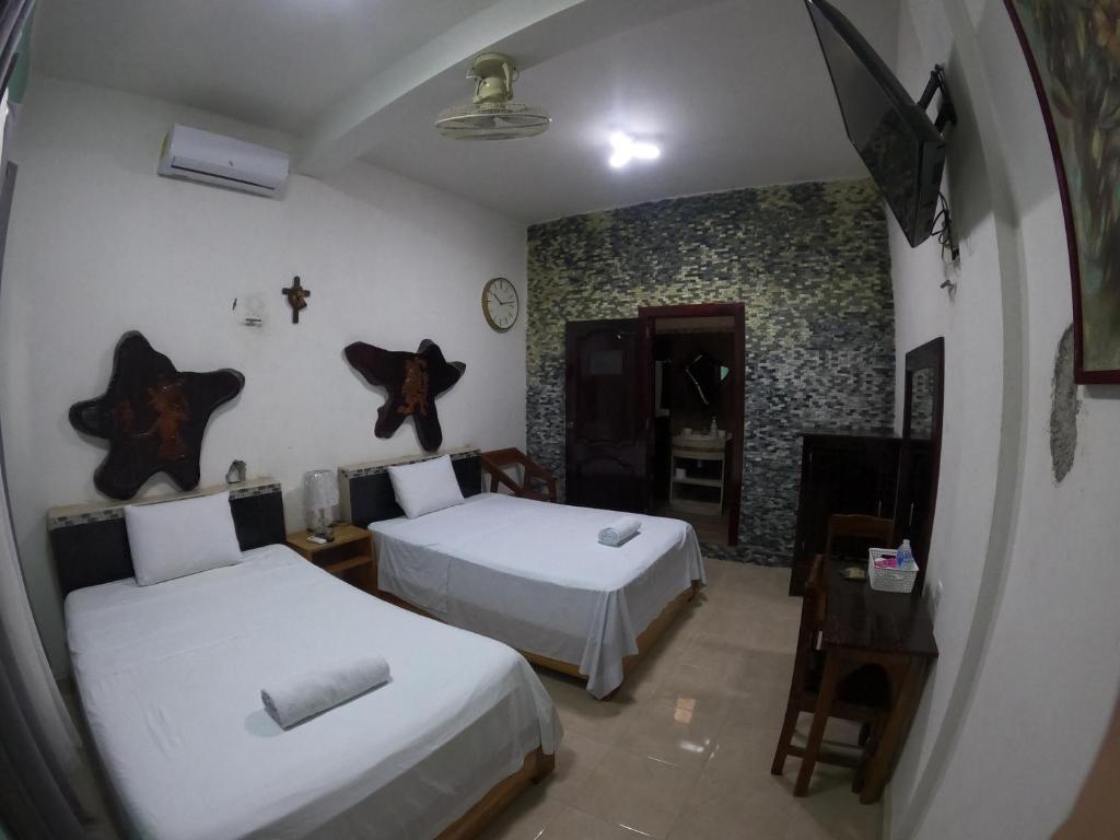 a bedroom with two beds and a table and a mirror at Bacalar in Bacalar