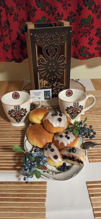 a plate of donuts on a table with two cups at Apartament Jagodzianka Biały Dunajec in Biały Dunajec