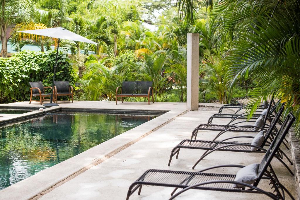 a row of chairs sitting next to a swimming pool at Ohana Villas in Santa Teresa Beach