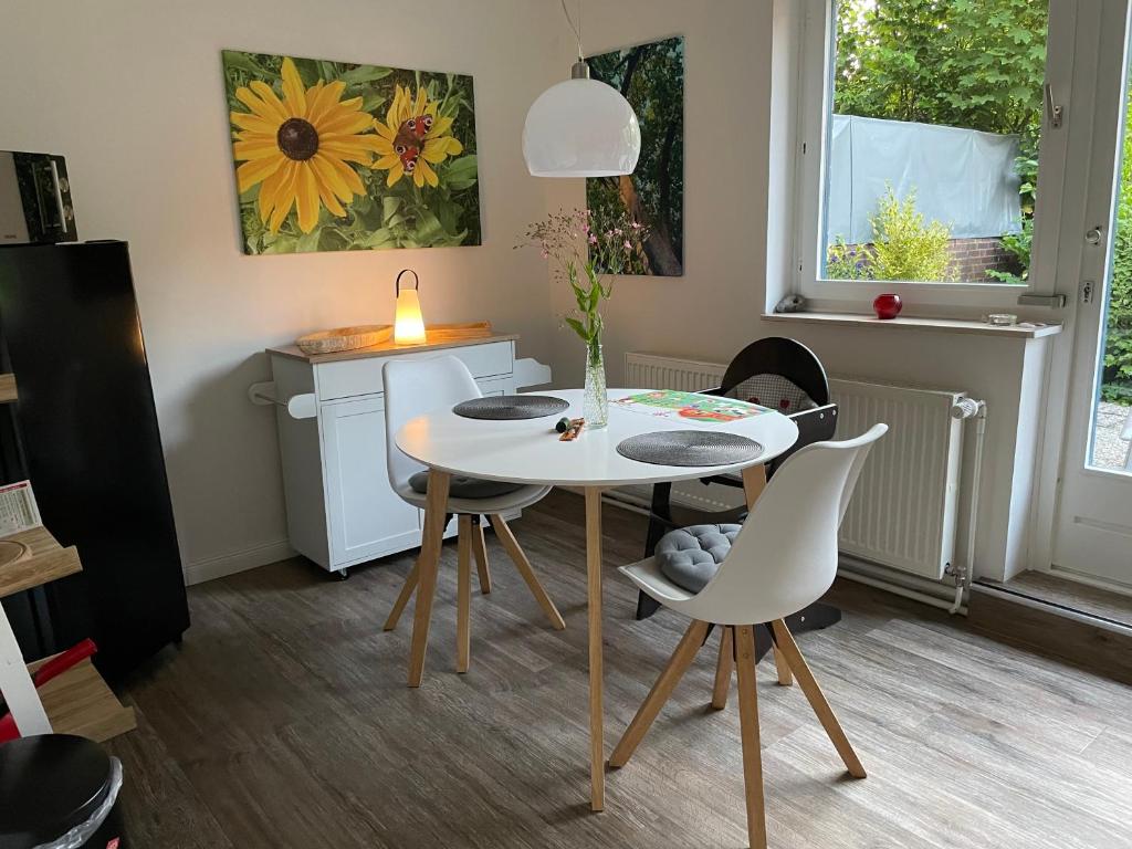 a dining room with a white table and chairs at HUUS UTSPANN FeWo mit Terrasse - 23 km vor Hamburg - in Seevetal