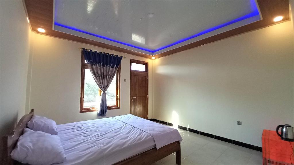 Un dormitorio con una cama con techo azul. en Benedict Guesthouse by Mori Hospitality, en Labuan Bajo