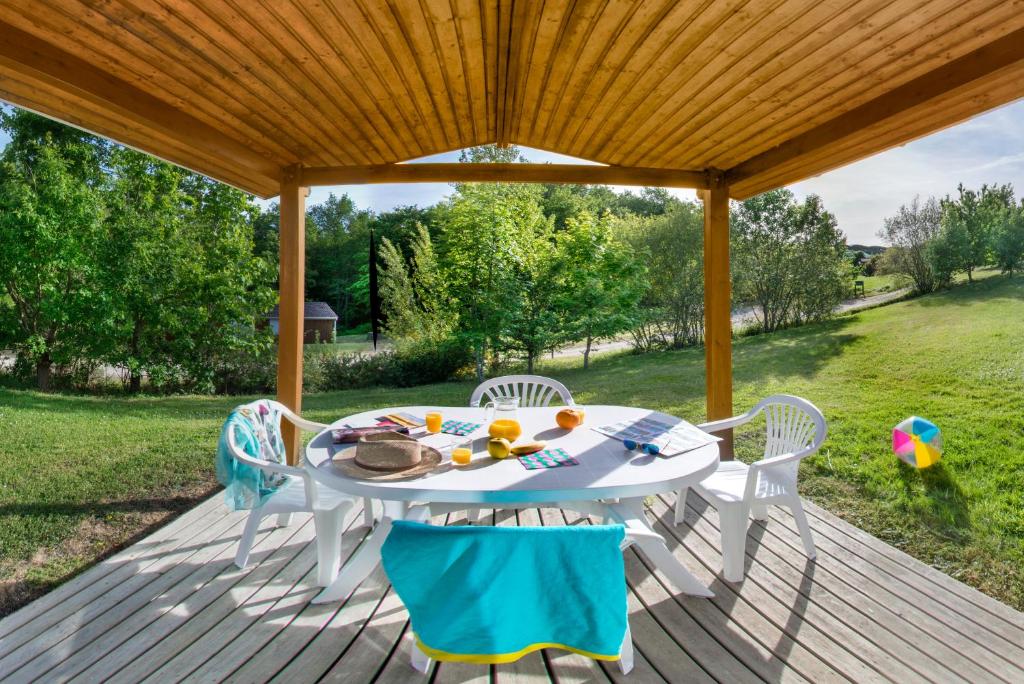 une table et des chaises blanches sur une terrasse en bois dans l'établissement LE HAMEAU DES ETOILES, à Fleurance