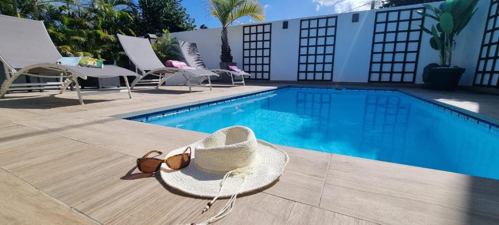 un sombrero y gafas de sol sentados junto a una piscina en charmante maison avec piscine, idéale famille en Saint-Pierre