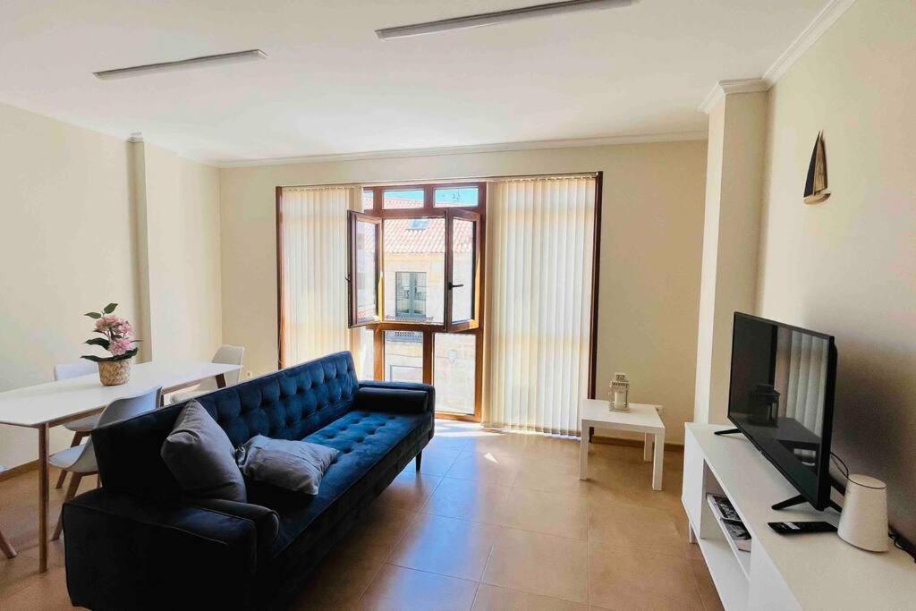 uma sala de estar com um sofá azul e uma televisão em VIVE HOME Vilanova de Arousa em Vilanova de Arousa