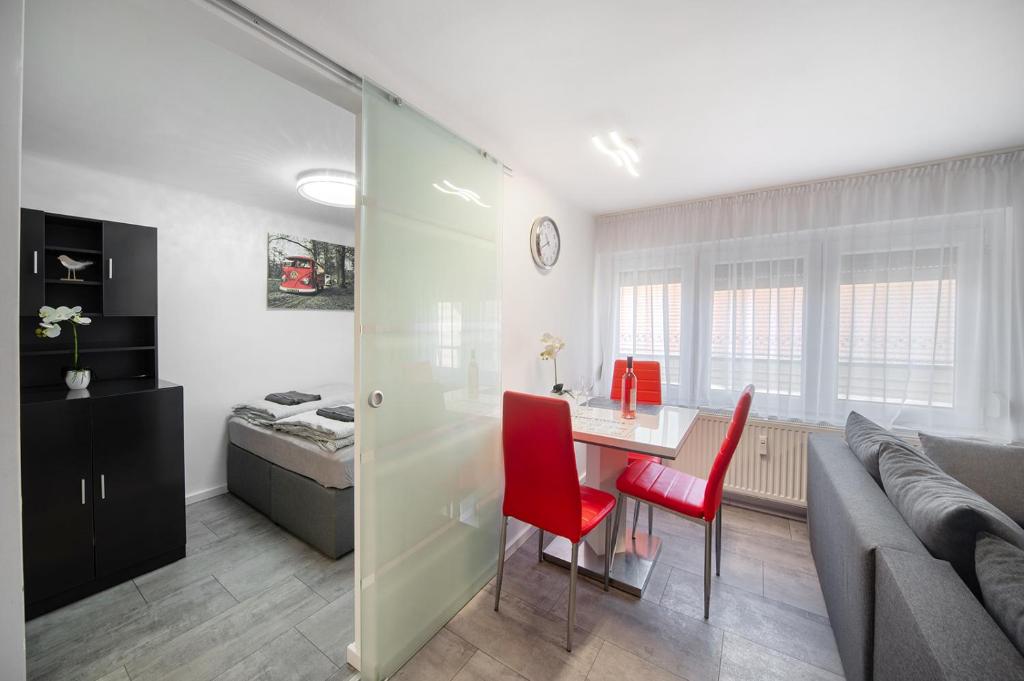 a kitchen and living room with a table and red chairs at Centroom Pécs Apartman in Pécs