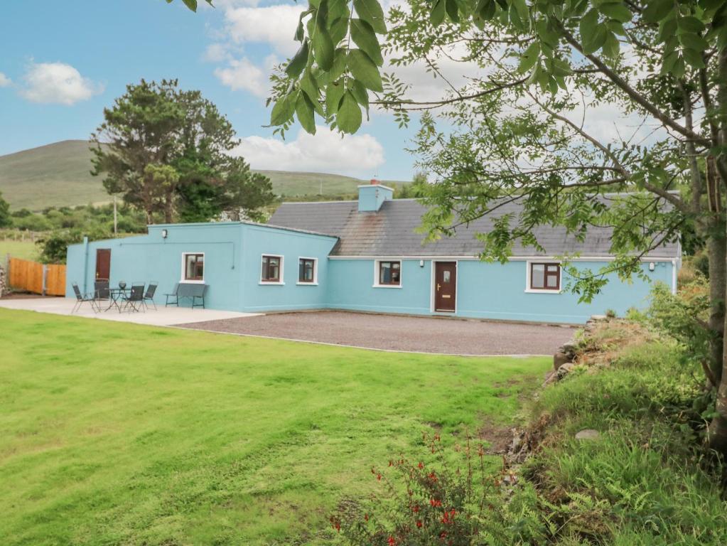 uma casa azul com um relvado verde em frente em Sweeney's Cottage em Beaufort