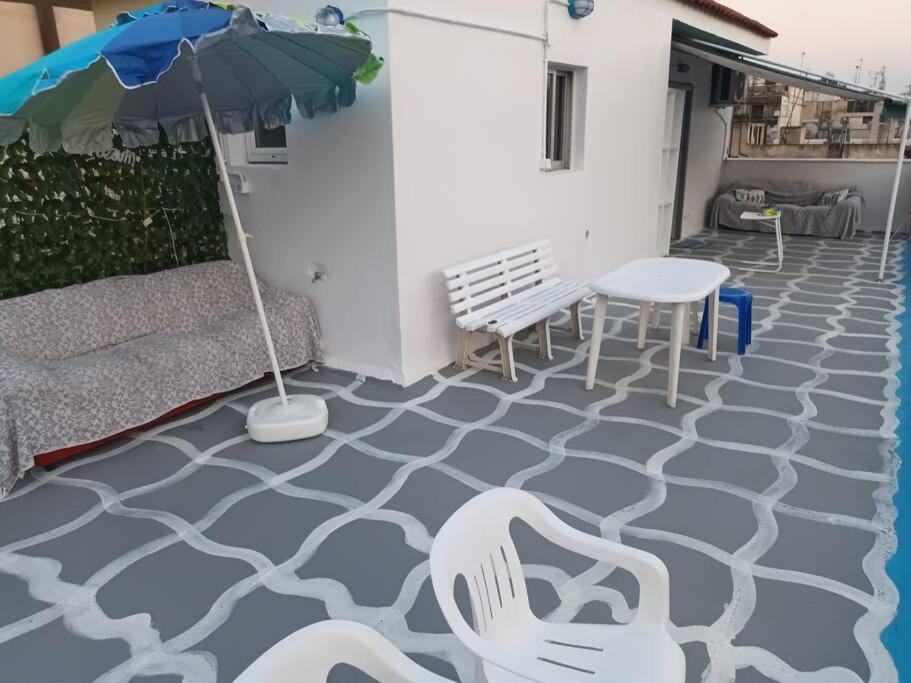 a patio with a table and chairs and an umbrella at Θέρετρο Γαλάζιου Ουρανού in Athens