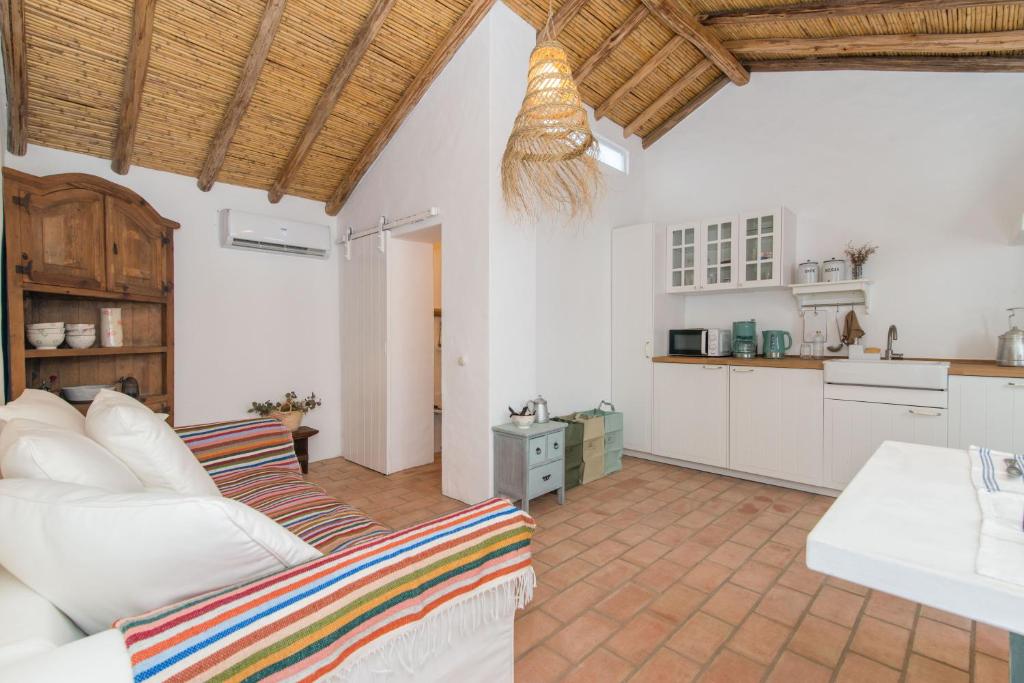 een woonkamer met een witte bank en een keuken bij Casa Formosa - Serena Tradição in Santa Luzia