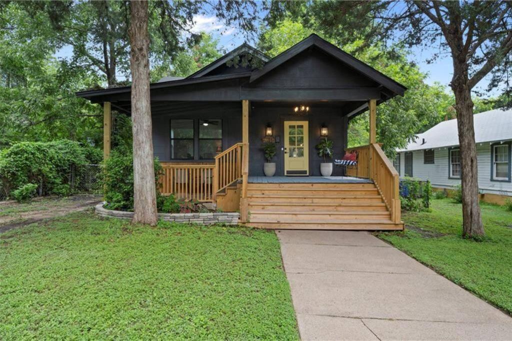 una casa con un gran porche de madera con puerta delantera en The Pinewood House, en Waco