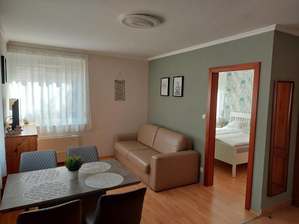 uma sala de estar com uma mesa e um sofá em Elek Apartmanház em Hajdúszoboszló