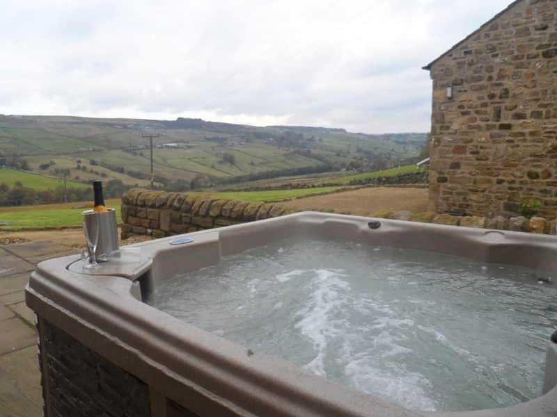 a bath tub with water in a stone building at Daisy Cottage in Keighley