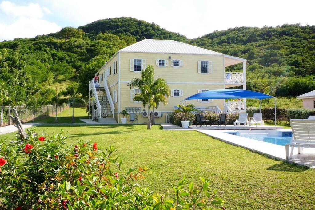 a house with a yard with a swimming pool at Palm breeze: sea view near Jolly Beach in Jolly Harbour