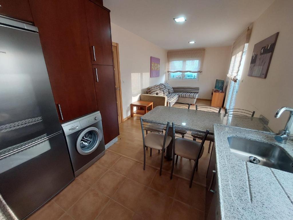 una cucina e un soggiorno con tavolo e lavatrice di Apartamento cerca de la playa a Finisterre