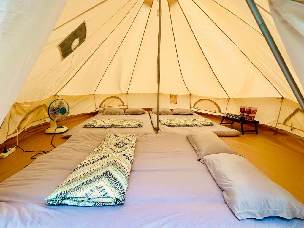 - un grand lit dans une tente avec des oreillers dans l'établissement SAY Camp Forest, à Cần Giờ