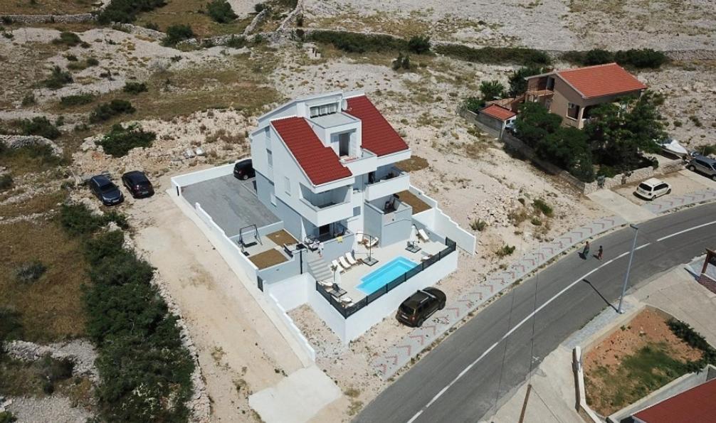 a white house with a swimming pool next to a road at Belvedere Premium in Novalja