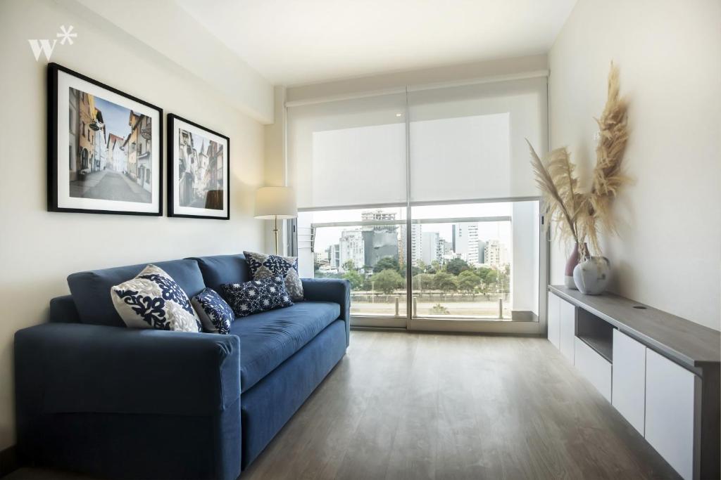 a living room with a blue couch and a large window at Connect by Wynwood House in Lima