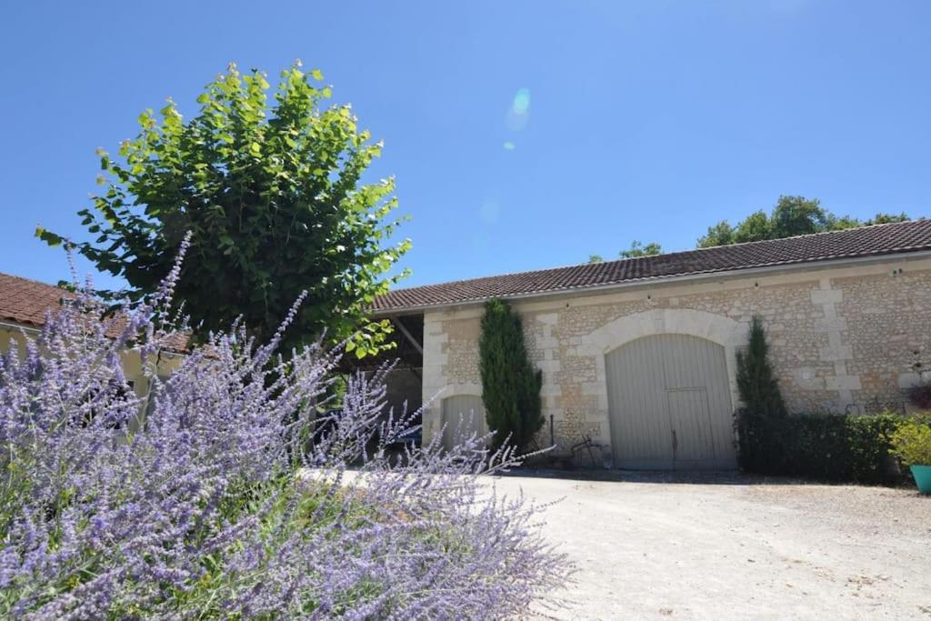 een huis met een garage met een boom en paarse bloemen bij Petite Maison au coin in Festalemps