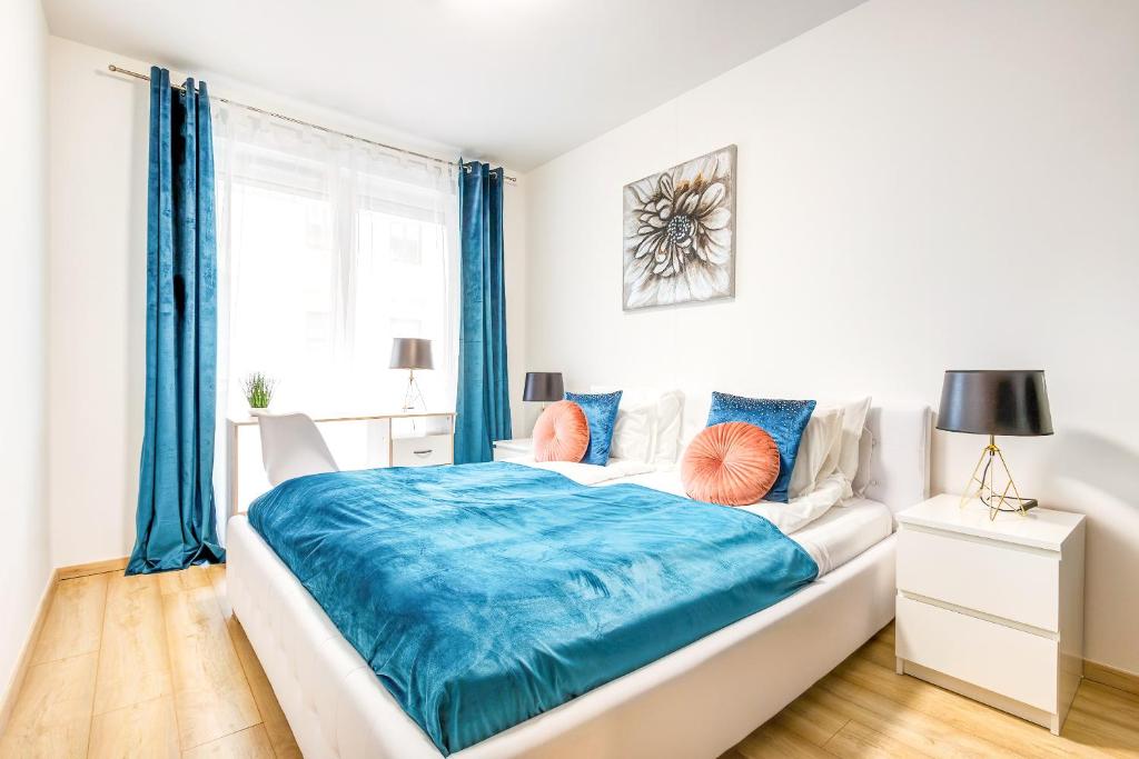 a white bedroom with blue curtains and a bed at Modern apartment with free garage and balcony in the downtown in Budapest