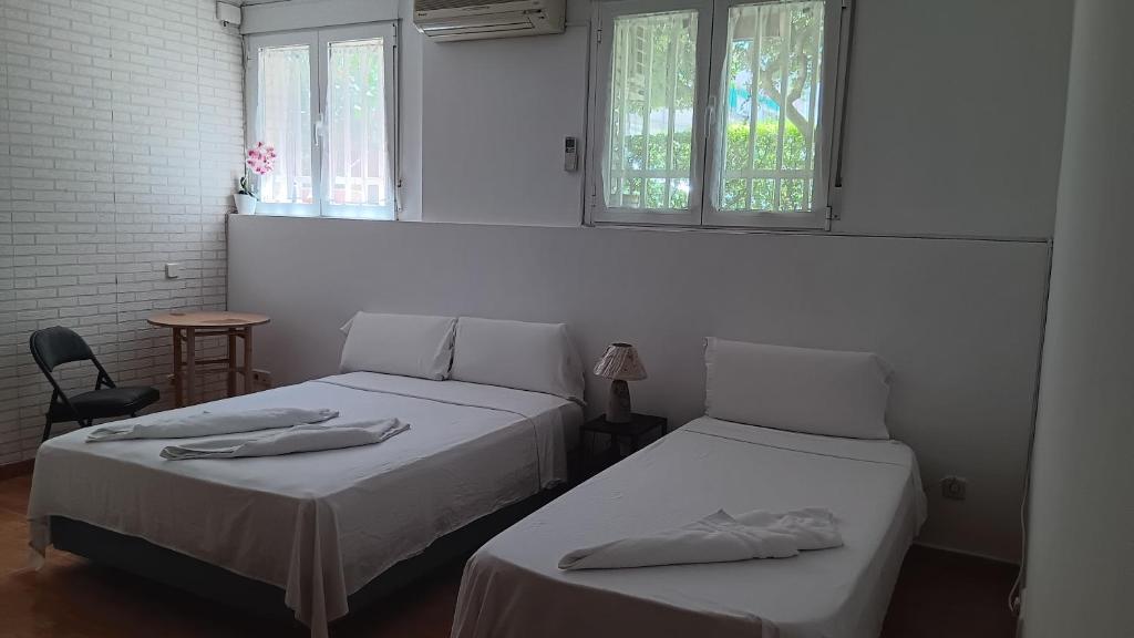 two beds in a room with two windows at El Colmenar Habitaciones in Madrid