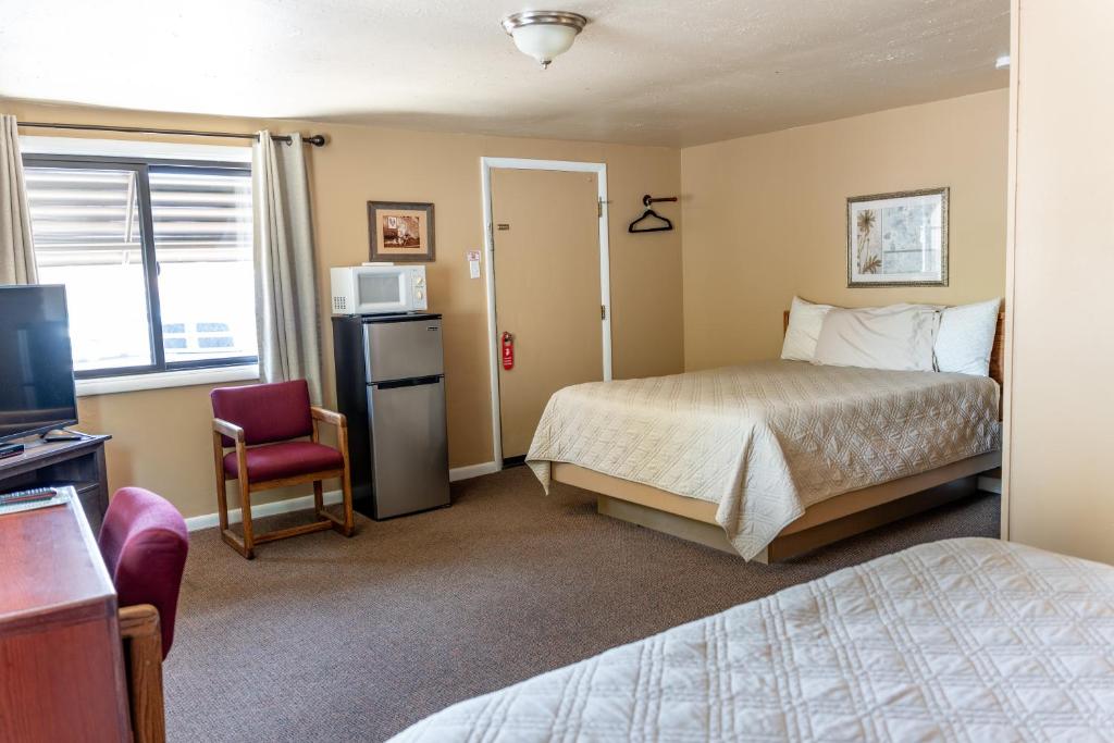 a hotel room with a bed and a refrigerator and a television at Oregon Trail Inn in Buhl