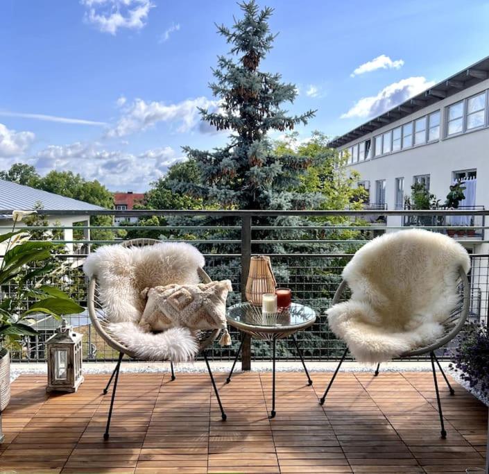 a patio with two chairs and a table with a cat on it at BALI HOME Stylische Wohnung mit Terrasse in Schönefeld