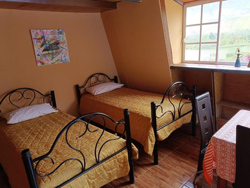 2 camas en una habitación pequeña con ventana en BUNGALOWS YAHUARCOCHA, en Ibarra