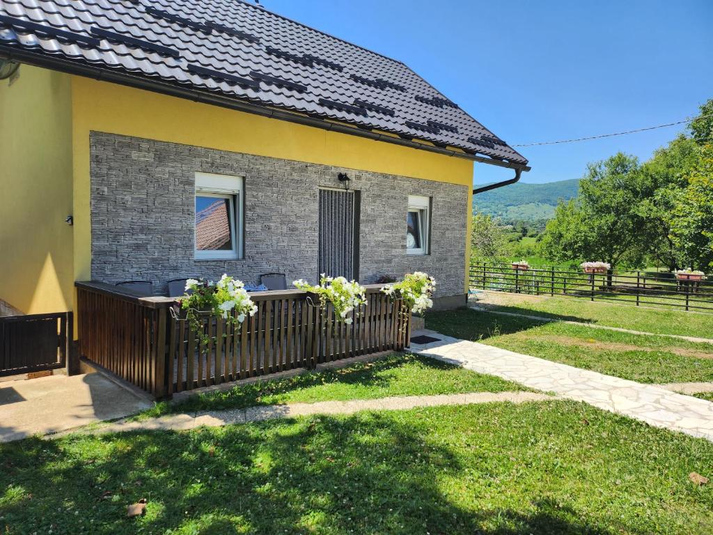 a house with a wooden fence in the yard at Apartment & Room TOMA in Smoljanac