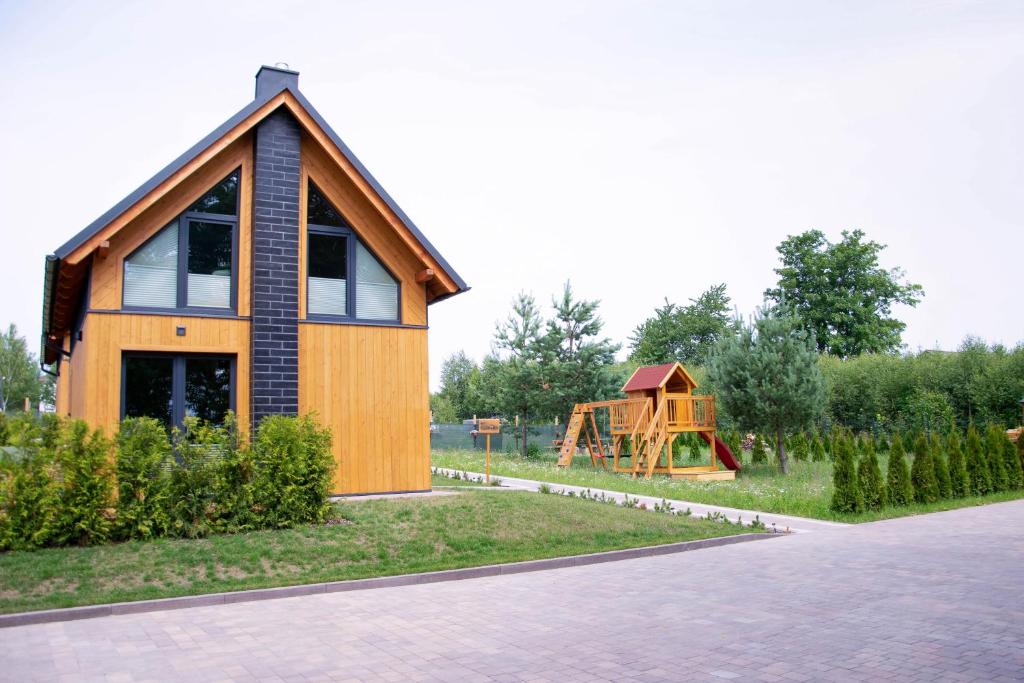 una pequeña casa de madera con un parque infantil en el fondo en STOLEMOWE Wzgórze Domek Leśnika, en Perlino