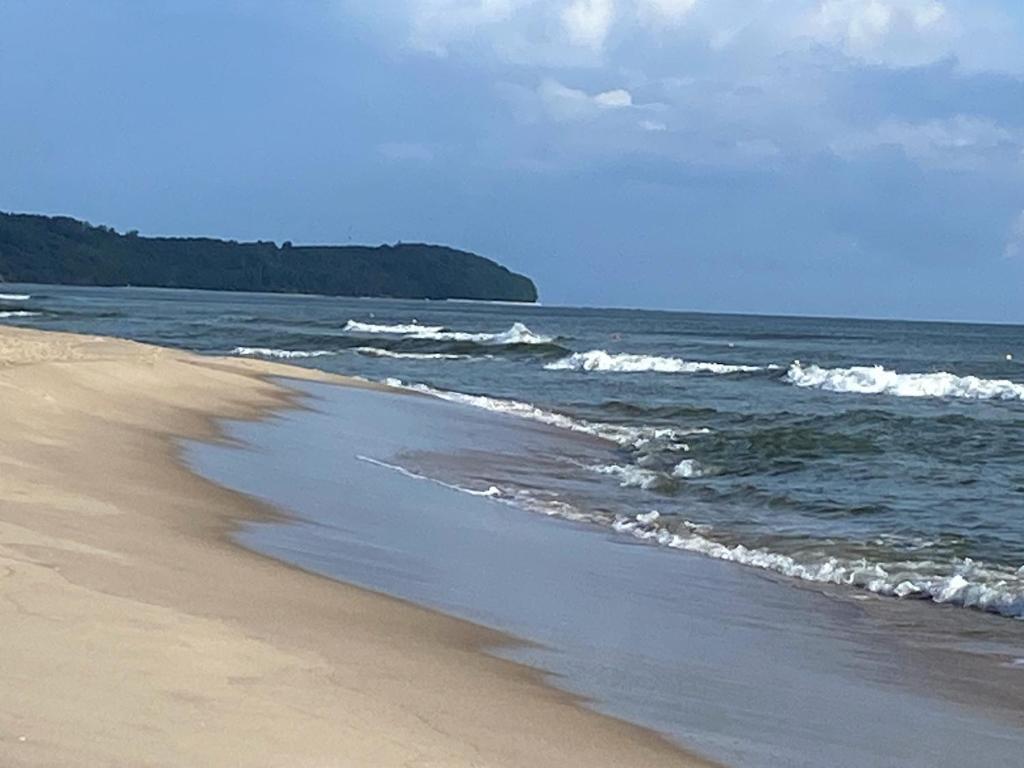 a sandy beach with waves in the ocean at Apartament Przy Plaży in Władysławowo
