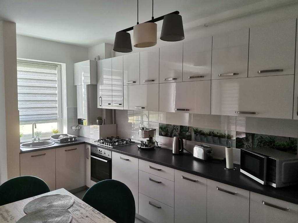 a kitchen with white cabinets and a black counter top at Apartmant Melinda M26 in Braşov