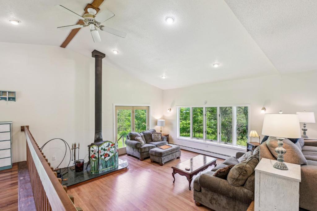 a living room with a ceiling fan and a fireplace at Charming and Scenic Gouldsboro Getaway with Patio! in Gouldsboro