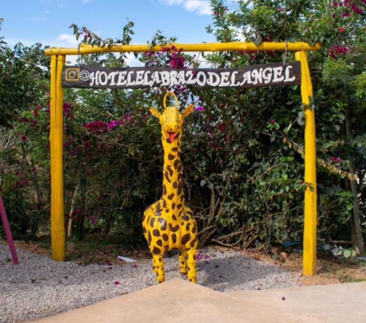 una estatua de jirafa parada frente a un cartel en HOTEL CAMPESTRE ABRAZO DEL ANGEL en Aratoca