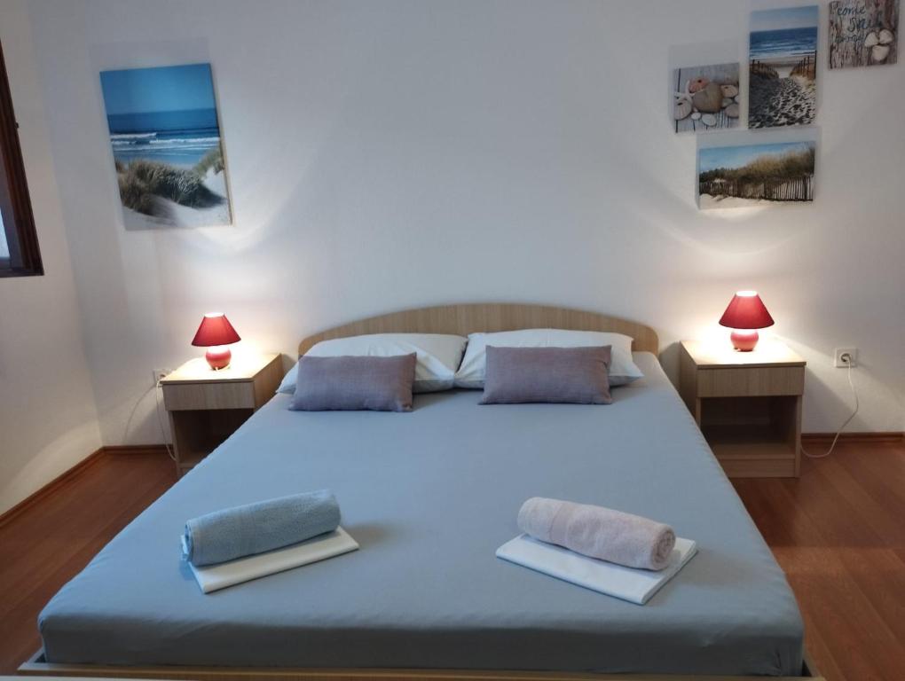 a bedroom with a large bed with two lamps at Soba Ivanka Nikšić in Karlobag
