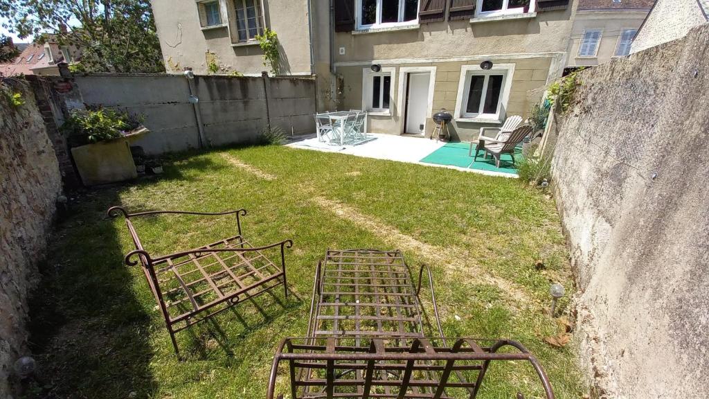 dos bancos de metal sentados en el césped en un patio en Gîte des Tanneurs, en Nogent-le-Rotrou