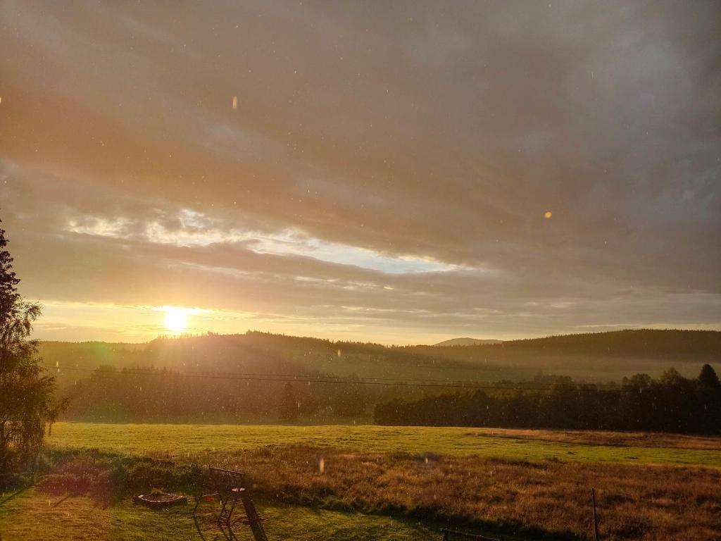 una puesta de sol en un campo con el sol en el cielo en Apartmán Bokova chata en Nové Hutě